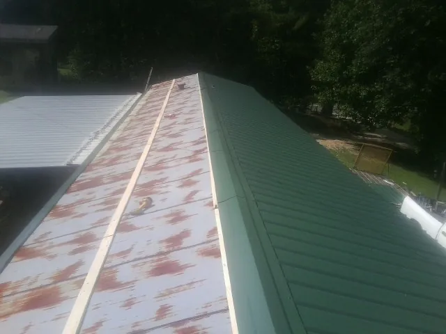 Old rusted panels beside newly installed green metal roofing — Wind Damage Roof Repair by Roofing Brothers in West Ossipee