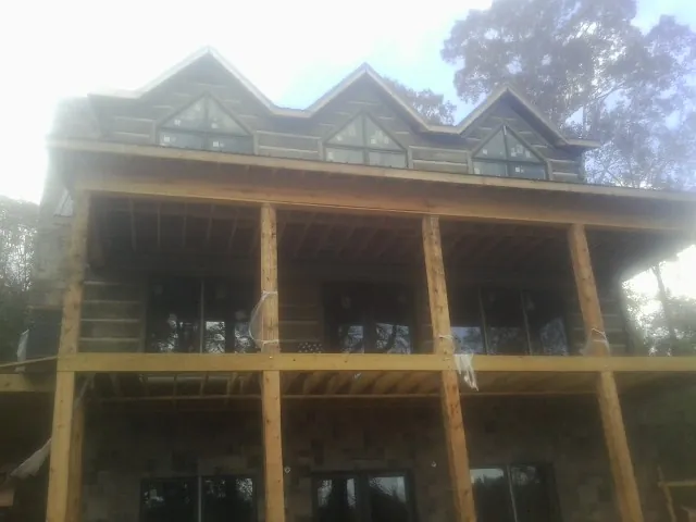 Dormers and porch framing on a large log home under construction — Roof Coating work by our crew in West Ossipee