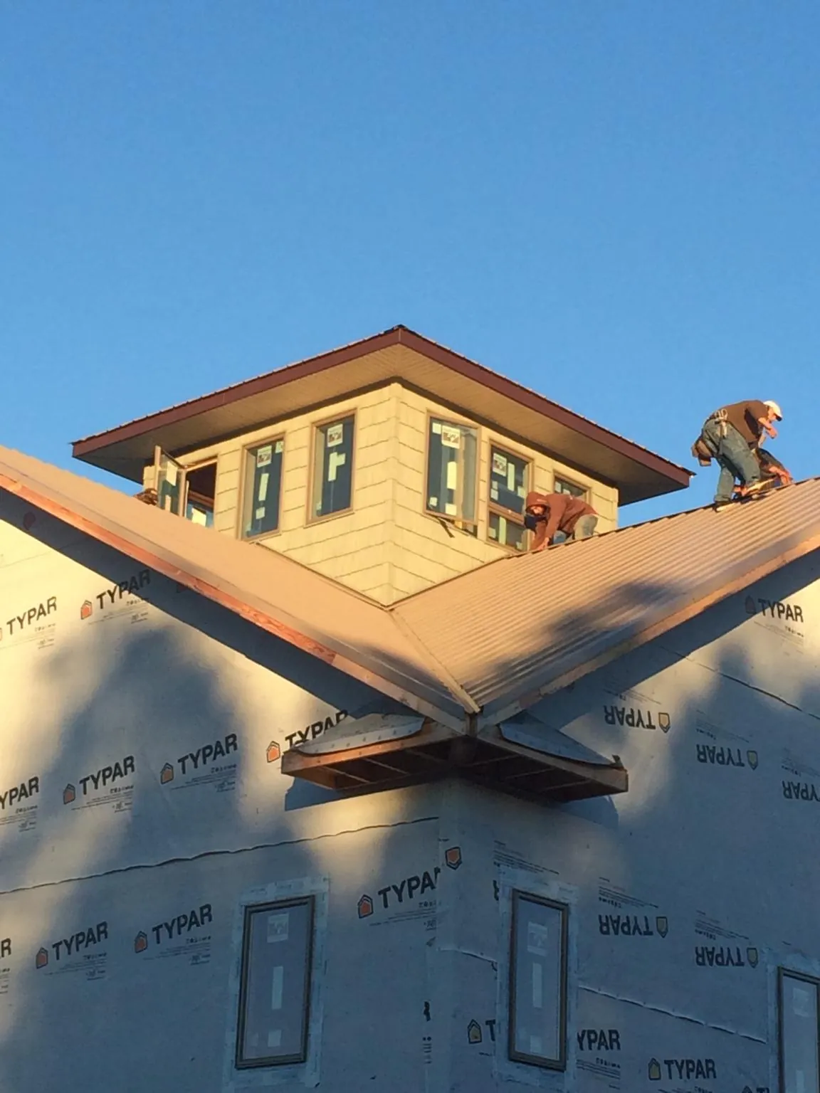 Roofers working around a rooftop cupola on a new metal roof at sunset — Roof Waterproofing in West Ossipee by Roofing Brothers